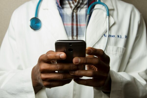 What is Medical Tourism? person wearing lavatory gown with green stethoscope on neck using phone while standing